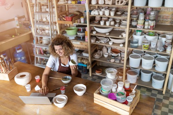 Female potter using laptop in art studio