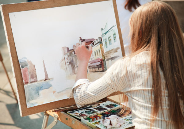 Young woman working on a watercolour painting outdoors